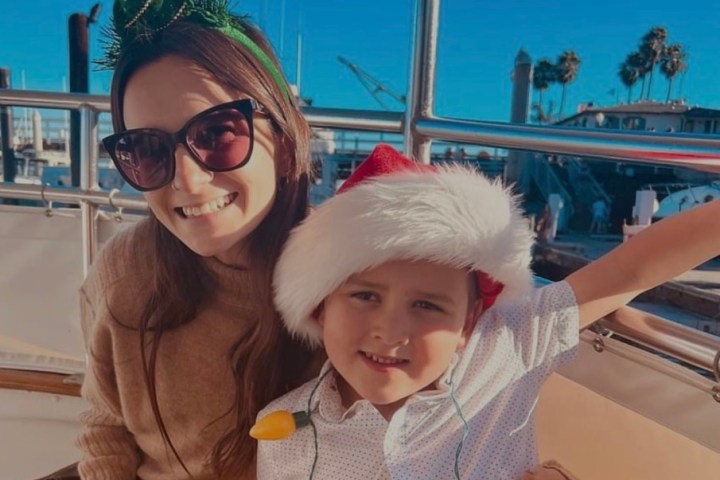 Woman and child in festive hats smiling on a boat under clear blue sky.