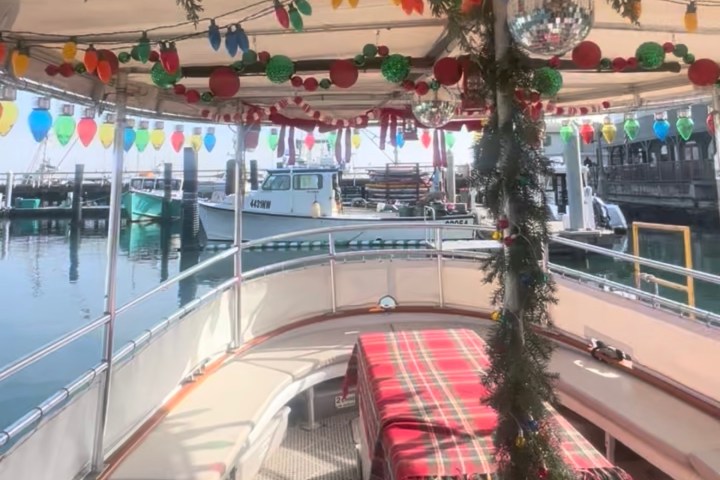 Boat deck decorated with colorful lights and Christmas garlands at a marina.