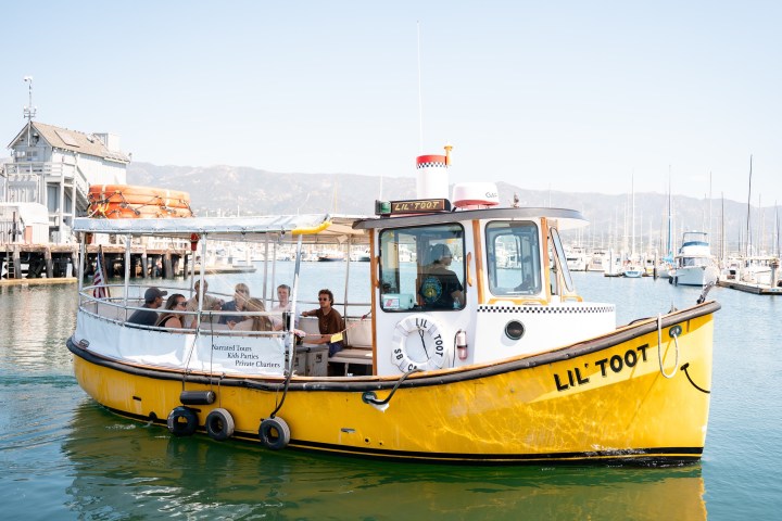 Yellow boat named 'Lil' Toot' with passengers in a marina.